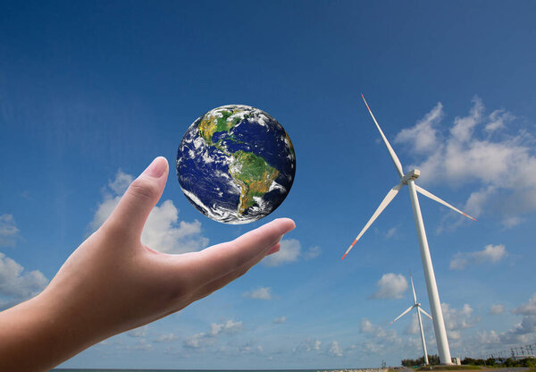 Рука держит глобус с ветряной турбиной позади него. Концепция концепции. Защищать окружающую среду. спасти мир от загрязнения чистой или возобновляемых источников энергии