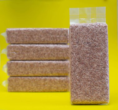 Pirinç taneleri plastik torbalarda vakumlanır. sarı arkaplanda izole edilmiş