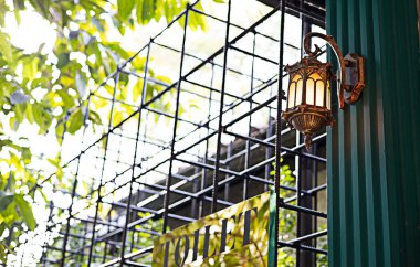 Klasik bir duvar lambası yeşil bir sütuna monte edilmiştir..