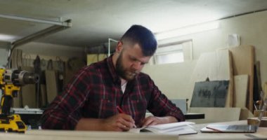 Marangozluk atölyesinde not defterine not alan sakallı bir Avrupalı.