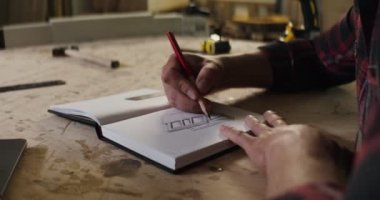 Marangozluk atölyesinde not defterine not alan sakallı bir Avrupalı.