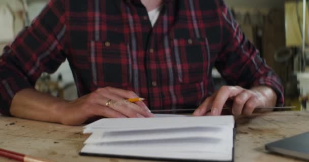 Man gör en penna ritning i en anteckningsbok med hjälp av en linjal närbild — Stockvideo