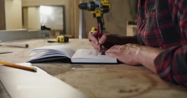 Hombre hace un dibujo a lápiz en un cuaderno usando una regla de primer plano — Vídeos de Stock