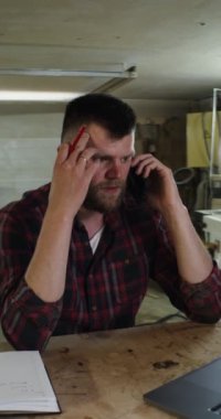 Bir marangoz dükkanında telefonla konuşan Avrupalı bir adam.