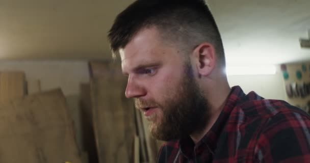 A european man talking by video call on a laptop in a carpentry workshop — Stock Video