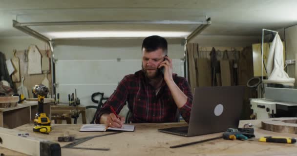 Seorang pria serius dari Eropa muncul berbicara di telepon di toko tukang kayu — Stok Video