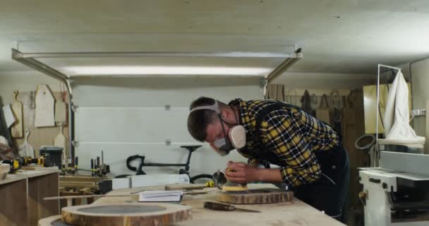 Om de aspect european în căști de protecție și o mască procesează un lemn — Videoclip de stoc