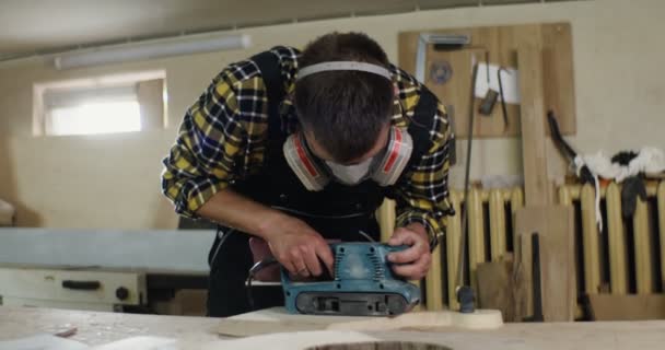 戴着防护性耳机和面罩的欧洲男子加工木料 — 图库视频影像