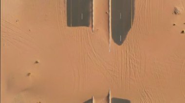 Kum tepecikleriyle kaplı çöl yolunun havadan görünüşü. Dubai, BAE.