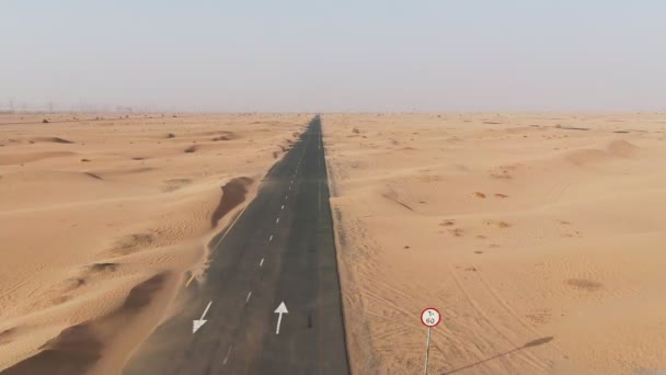 Vertical panning from a quadcopter. White car is driving on road in the desert — Stock Video