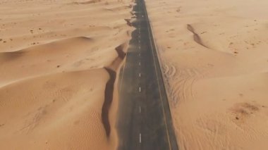 Kum tepecikleriyle kaplı çöl yolunun havadan görünüşü. Dubai, BAE.