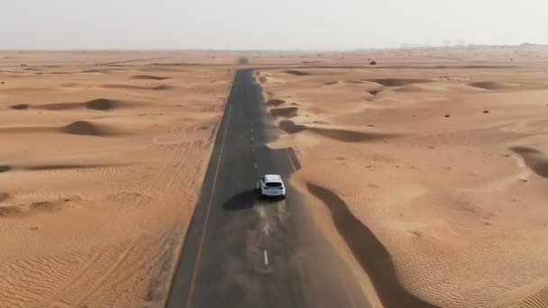 Вертикальне панорамування з квадрокоптера. Білий автомобіль їде по дорозі в пустелю — стокове відео