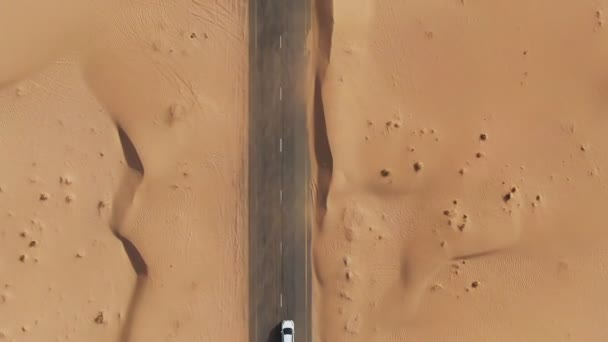 Verticaal hijgen vanuit een quadcopter. Witte auto rijdt op de weg in de woestijn — Stockvideo