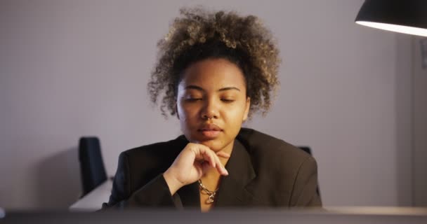 Schwarzes Mädchen im Anzug blickt lächelnd auf Monitor und wackelt im Büro mit den Händen — Stockvideo