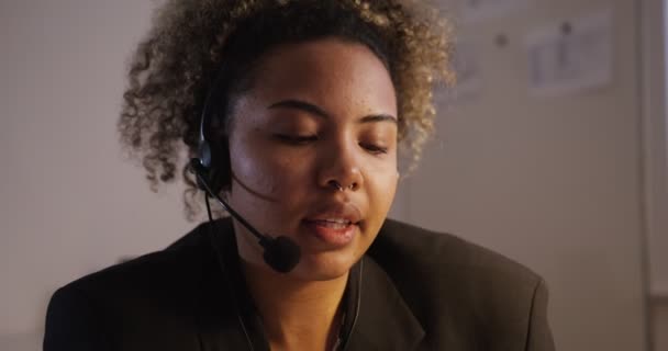 Dívka v bundě se sluchátky s mikrofonem mluví, poslouchá zblízka — Stock video