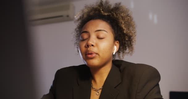 Afrika flicka med hörlurar talar aktivt blickar åt sidan, närbild — Stockvideo