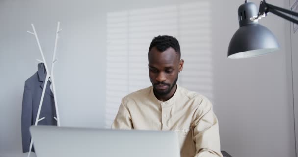 Nero ragazzo con la barba lavora in un ufficio moderno digitando sul computer portatile — Video Stock