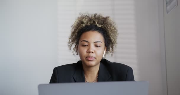 Negro chica está hablando activamente con el ordenador portátil abierto y auriculares de cerca — Vídeos de Stock