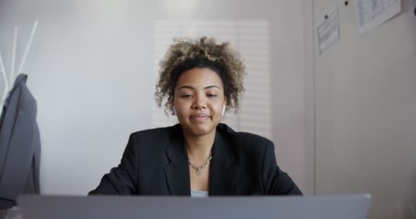 Ebony flicka hälsar och aktivt samtalar med öppen laptop och hörlurar närbild — Stockvideo