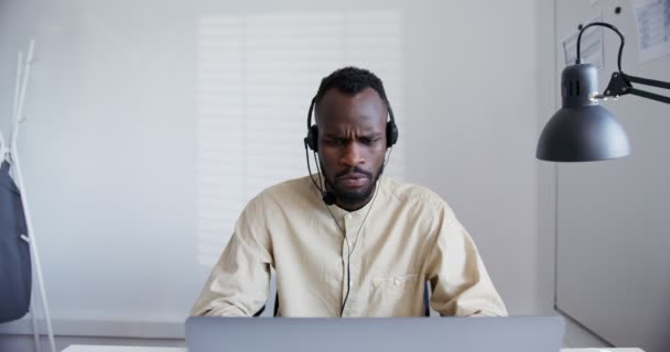 Чорний хлопець носить навушники з мікрофоном, криками, лабіринтами та типами — стокове відео