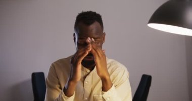 Sakallı siyah adam dizüstü bilgisayarını alıp ofiste gözlerini ovuşturuyor.