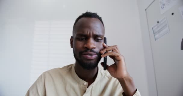 Noir gars avec une barbe parle par téléphone tandis que assis dans le bureau — Video