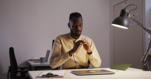 Noir gars avec une barbe parle sérieusement par téléphone tout en étant assis dans le bureau — Video