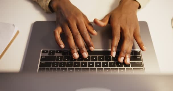 Zwarte man typen op een laptop in een kantoor onder het licht van de tafellamp — Stockvideo