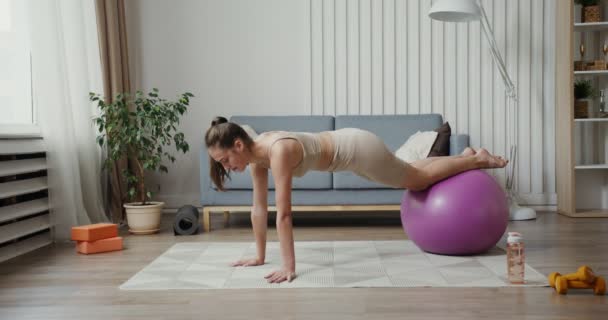 Chica europea vestida con ropa deportiva haciendo ejercicios de fuerza con pelota — Vídeos de Stock