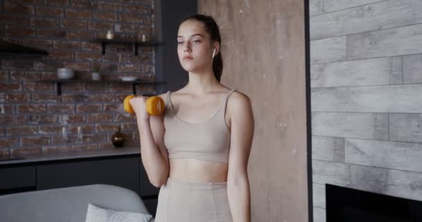 Chica europea vestida con ropa deportiva haciendo ejercicios con mancuernas — Vídeo de stock
