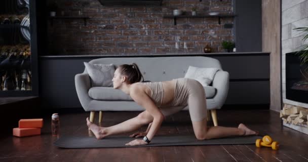 Evropská dívka oblečená ve sportovním oblečení se táhne na gymnastické podložce — Stock video