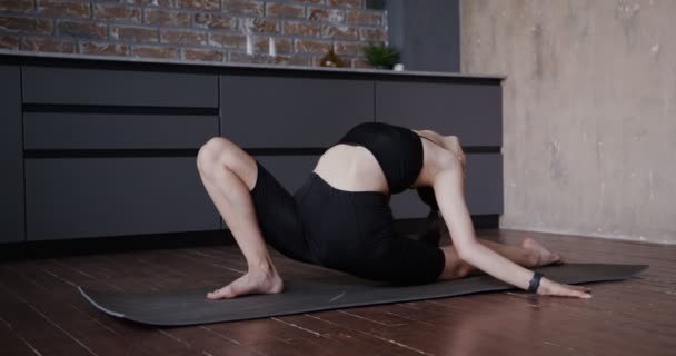 Европейская девушка в спортивной одежде растягивается на гимнастическом коврике — стоковое видео