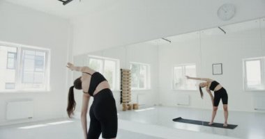 Spor giyimli Avrupalı kız kollarını kaldırarak yan yana kıvrılıyor.