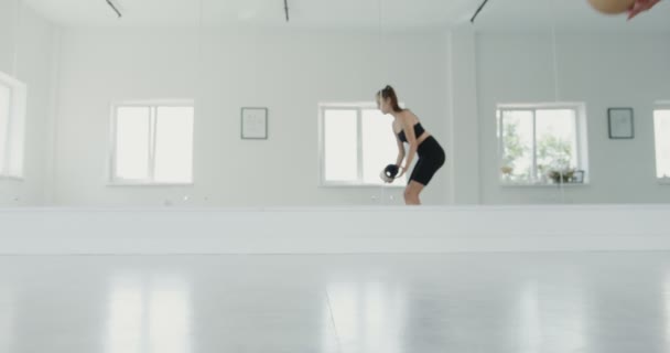 Europejska dziewczyna w odzieży sportowej przychodzi do sali gimnastycznej i rozpoczyna rozgrzewkę — Wideo stockowe