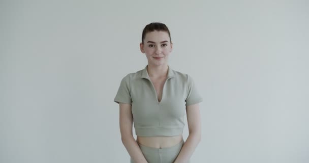Европейская девушка в спортивной одежде улыбается, глядя в камеру — стоковое видео