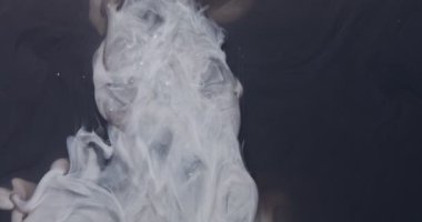 Beyaz boya şiddetli bir şekilde siyah suya hücum eder, kıvrılır ve yayılır.