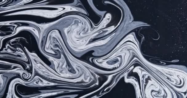 Weiße Farbe fließt in glitzerndes Schwarz, abstrakte Farben wirbeln und explodieren. — Stockvideo