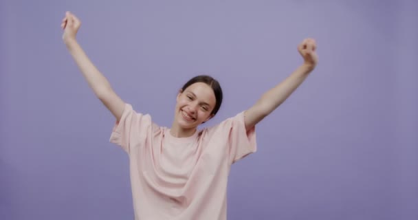 Egy fiatal nő táncol és ugrál, boldogan integet a karjával és széles körben mosolyog.. — Stock videók