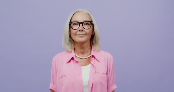 Adult well-groomed woman with gray hair, wearing glasses smiles into camera — Stock Video