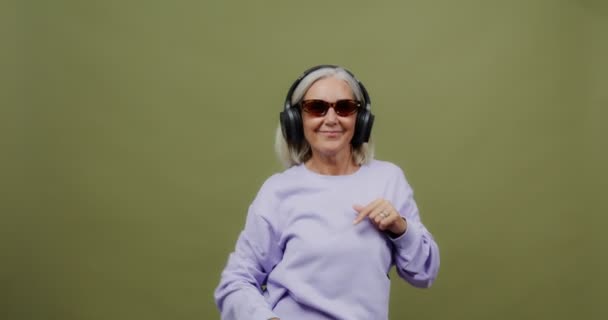 Uma mulher adulta usando fones de ouvido dança ritmicamente rock and roll — Vídeo de Stock