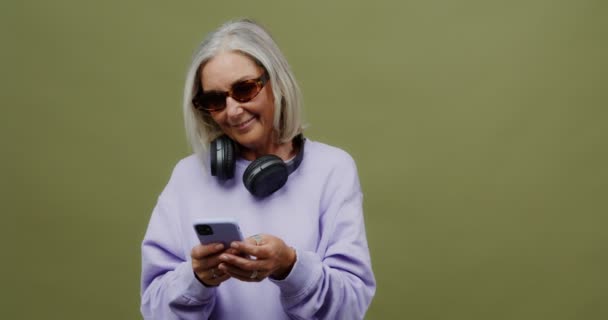 Uma mulher adulta com um telefone nas mãos enviando mensagens e sorrindo — Vídeo de Stock