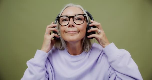 Seorang wanita dewasa memakai headphone dan mulai menari — Stok Video