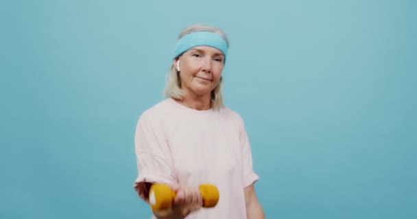 Uma mulher adulta fazendo exercícios para os braços com halteres — Vídeo de Stock