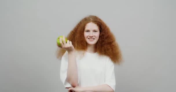 Gyönyörű vörös hajú lány, zöld almát eszik.. — Stock videók