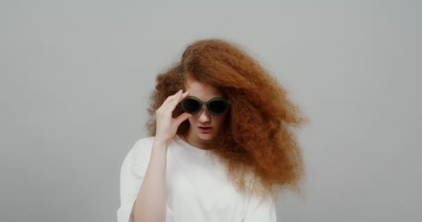 Красива руда дівчина з пишним волоссям одягає сонцезахисні окуляри — стокове відео