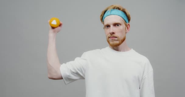 Un type roux lève un petit haltère une fois et vérifie ses biceps — Video