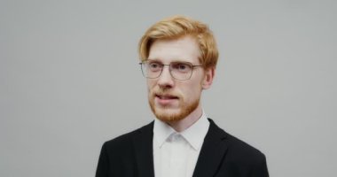İş elbisesi giymiş kızıl saçlı bir adam ciddi bir şey söylüyor.