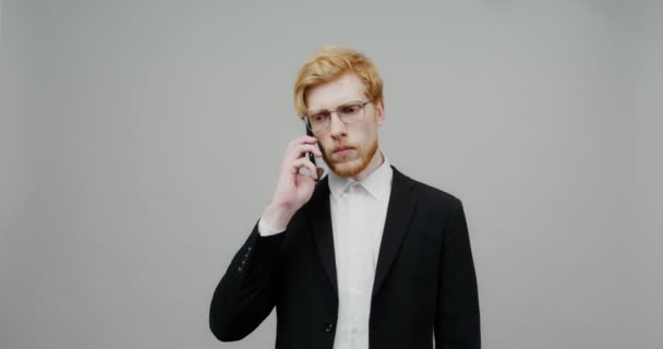Ένας σοβαρός τύπος ντυμένος με ένα επαγγελματικό κοστούμι, μιλάει σε ένα κινητό τηλέφωνο — Αρχείο Βίντεο