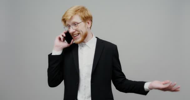 एक व्यवसाय सूट मध्ये परिधान एक गंभीर माणूस मोबाइल फोनवर बोलत आहे — स्टॉक व्हिडिओ