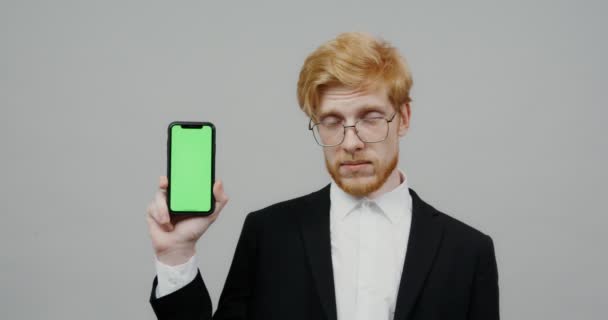 Een man gekleed in business suit, houdt een mobiele telefoon met een scherm aan de camera — Stockvideo